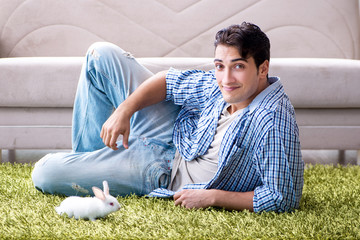 Young man playing with pet rabbit at home