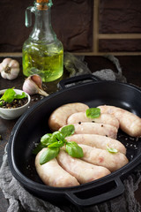 Raw homemade sausages on slate background, with basil and spices. Copy space.