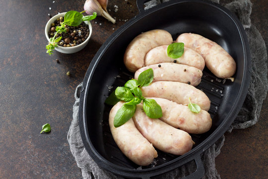 Raw homemade sausages on slate background, with basil and spices. Copy space.