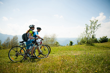 Obraz premium ACTIVE Young couple biking on a forest road in mountain on a spring day