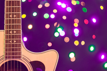 A part of yellow acoustic guitar with New Year or Christmass garlands on a blue background. Celebrating atmosphere.