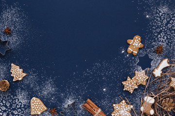 Christmas background with gingerbread and snow on navy colored surface. Holiday mood card. Top...