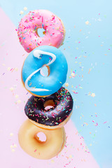 falling doughnuts chain - mix of multicolored sweet donuts with sprinkles on blue and pink...