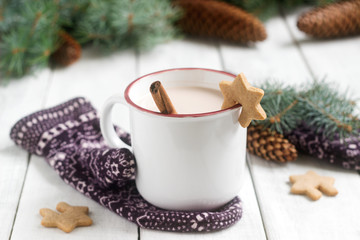 Obraz na płótnie Canvas Cocoa or hot chocolate with cinnamon and gingerbread on a background with mittens, fir branches and cones.