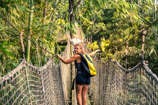 Cara&iuml;bes, Martinique, jardin de balata : femme qui traverse un pont suspendu