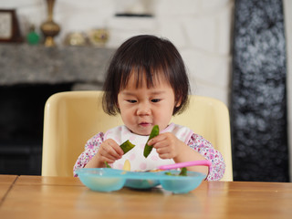 baby girl eating vegetable at home