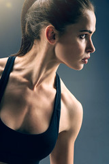 Fototapeta na wymiar Exercising hard. Profile of a serious female athlete wearing a sports bra focusing her attention on something during an intensive training session.