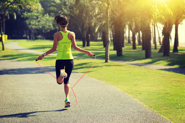 Fototapeta premium Young fitness woman jumping rope at tropical park