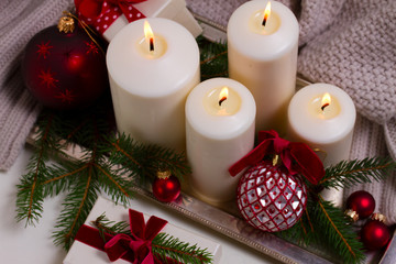 Four white burning advent candles with christmas decorations