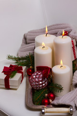 White glowing advent candles with christmas decorations on silver tray