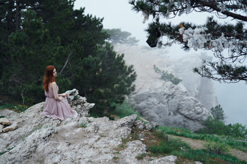 Woman looks at nature, foggy weather, rock, cliff