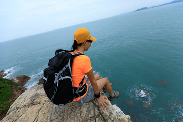 woman backpacker enjoy the view on seaside mountain top cliff