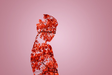 Mysterious lady. Waist up shadowgraph of a girl looking into the camera while standing against the leaves background.