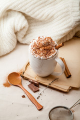 Cup of cocoa with cinnamon, whipped cream and chocolate. Textile background. Scandinavian winter concept. Vertical composition.