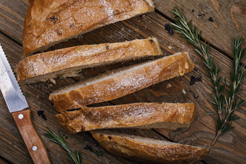 Freshly cooked bread cut into slices with rosemary close-up, top view