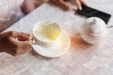 Convenient cup. Young visitor of a comfortable cafe holding a while cup with hot tea while having a relaxed breakfast