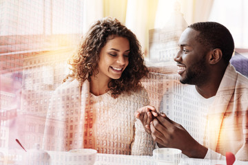 Extremely happy. Close up of positive pleasant woman looking at the wedding ring on her finger while her man holding her hand and smiling