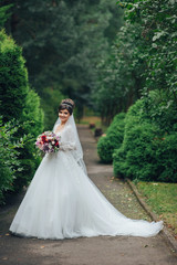 Pretty bride sits on a fountain in the garden