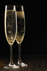 Two glasses of sparkling wine, close up. Black background.