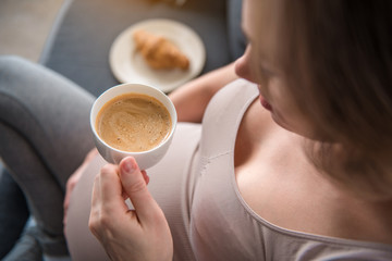 Top view close up of serene expectant mother holding cup of hot espresso