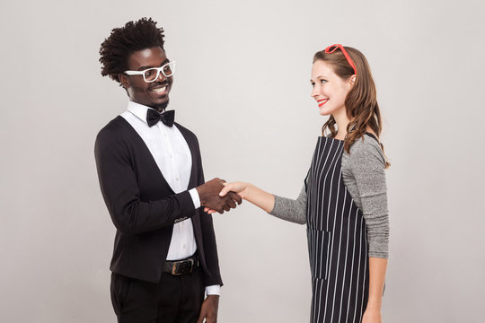 African man and freckles caucasian woman handshake and toothy smiling