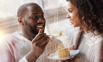 Pleasant date. Optimistic young couple looking at each other with love while eating tasty dessert...