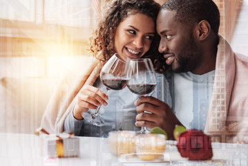 True love. Close up of young optimistic couple having wonderful date while looking at each other and holding glasses with wine