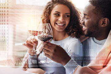Lovely atmosphere. Close up of joyful young couple drinking wine while looking at each other and showing true emotions