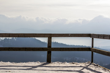 Wooden boards railing in winter mountains