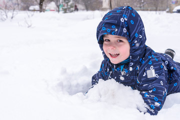 a little child looks out of the snow or pieces of ice. A child plays with snow