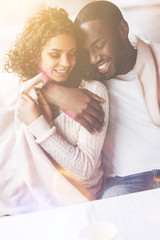 Love your hands. Smiling black woman covering shoulders with plaid nestling up to her boyfriend sitting together in cafe