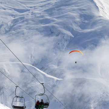 Chair-lift and paraplane in haze on ski resort at cold winter day