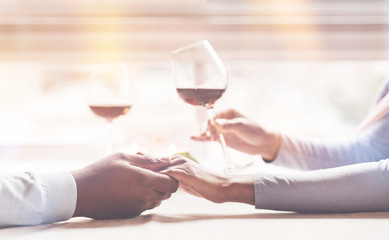 Your support. Black man wearing white sweater keeping his right hand on the table while touching hand of his girlfriend
