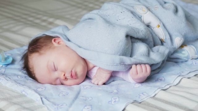 Newborn baby sleeping on a bed covered with a blue blanket
