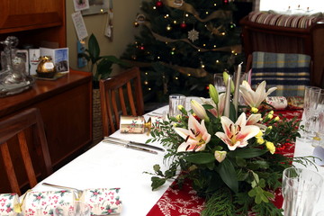 Beautiful floral centerpiece with candles on a festive dining table laid ready for Christmas Dinner in a traditional home