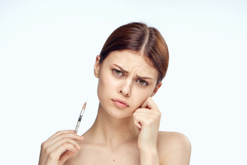 Young beautiful woman on white isolated background holds a syringe, plastic surgery
