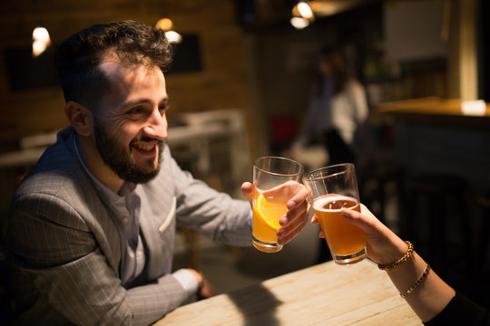 Smiling man toast with craft beer in a pub