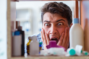 Sick ill man looking for medicines at farmacy shelf