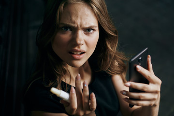 Obraz premium Young beautiful woman holding a phone and a hygienic lipstick