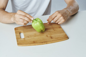 Man is sitting at a table, pepper on a cutting board, vegetables, vegetarian, diet