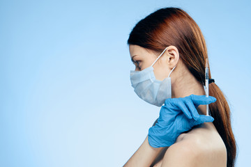 Young beautiful woman on a blue background in medical gloves holds a syringe, medicine, plastic, surgery