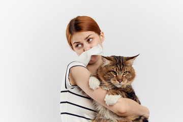 Young beautiful woman on a light background holds a cat, an allergy to pets