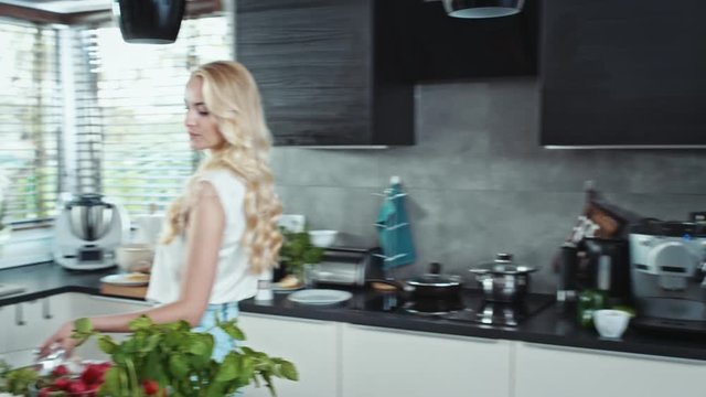 Charming blonde cooking in the cosy, bright kitchen