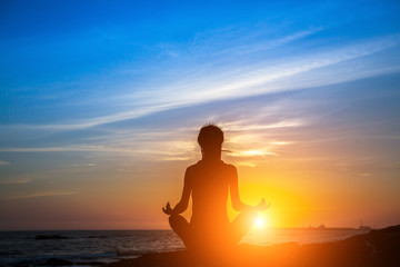 Fototapeta premium Meditation yoga woman silhouette on the Sea during amazing sunset.
