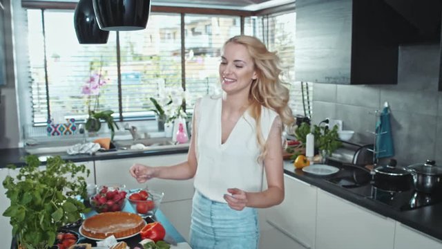 Charming blonde cooking in the cosy, bright kitchen