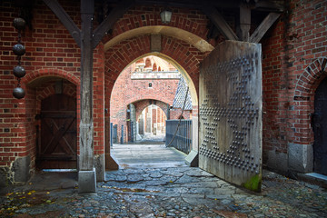 Gate in Castle of the Teutonic Order in Malbork, Poland. Red brick wall and cobblestone.
