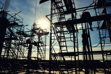 silhouette group of worker in safety uniform install reinforced steel column in construction site during sunset time industrial concept - obrazy, fototapety, plakaty