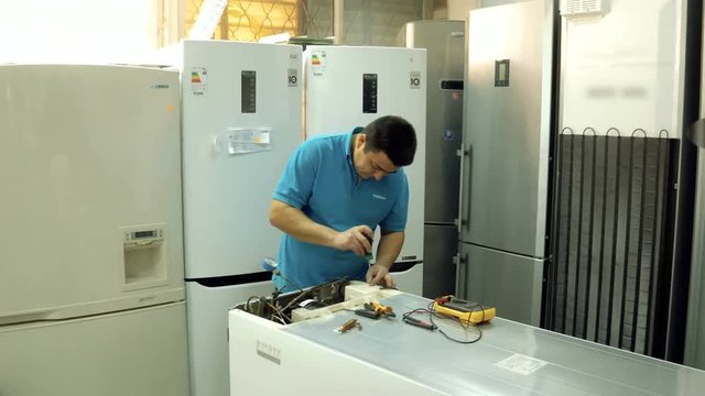 Service center. Electronics repair shops. A man repairs the fridge. Aluminum brazing.