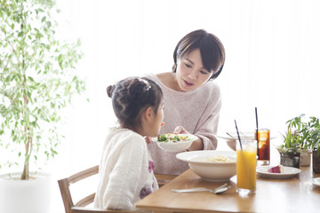 Dad, mommy and daughter are eating pasta.