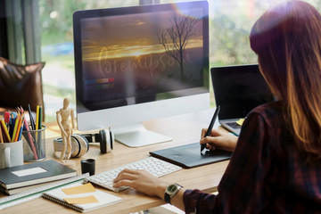 Young hipster graphic designer woman using digital graphic tablet while working at modern office,...